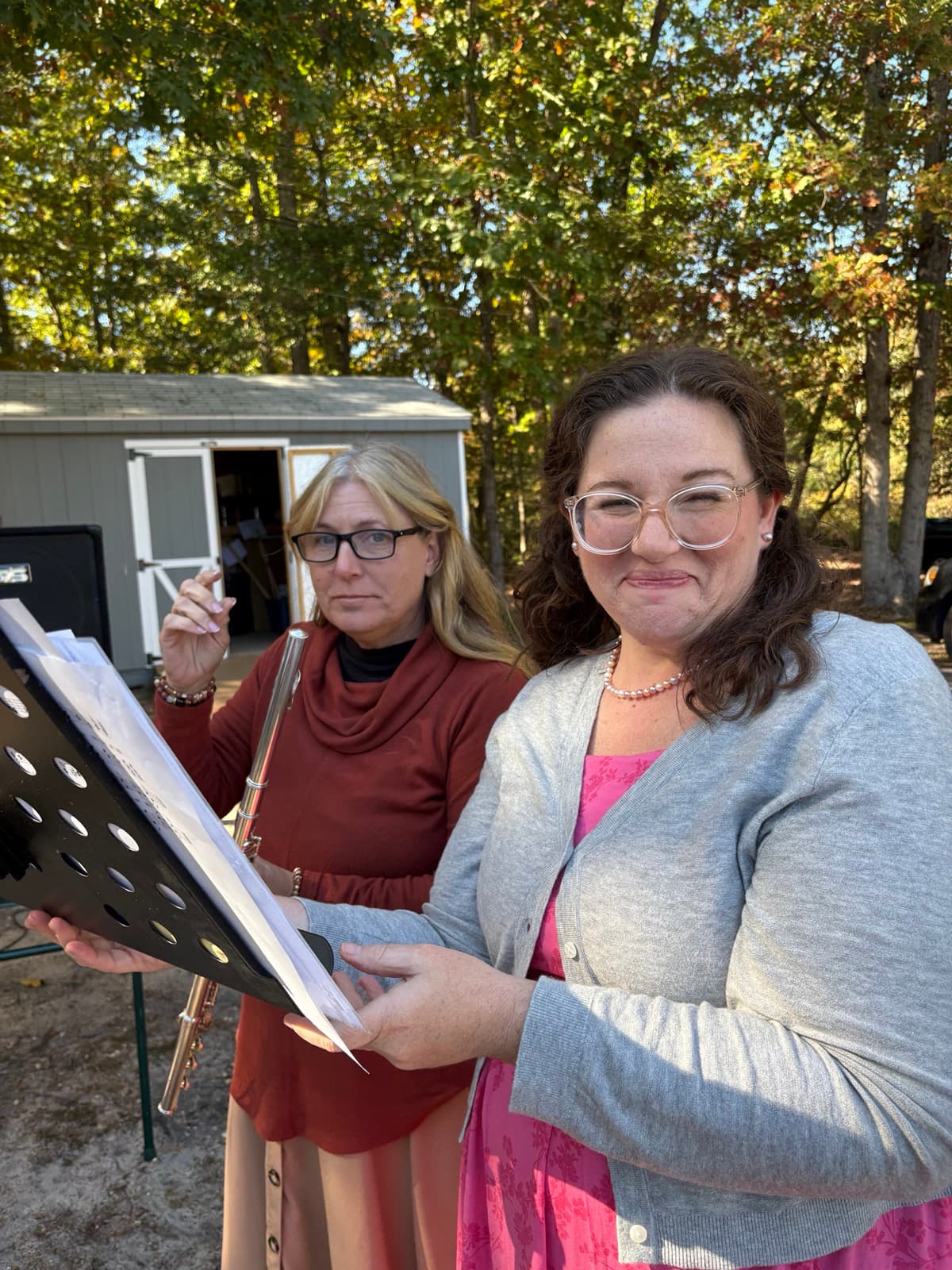 Two church members with a flute and sheet music at an outdoor hymn sing